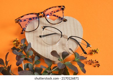trendy fashion eye glasses and plant branch on wooden heart shaped stage on orange background, close up mock up copy space, original composition - Shutterstock ID 2170126871