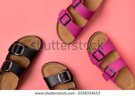 Trendy fashion footwear mockup. Leather pink and black sandals birkenstocks on pink background top view flat lay. Unisex summer shoes, genuine leather flip flops with cork soles 