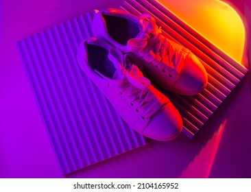 Trendy fashion white sneakers on abstract bright background. Neon lights on casual shoes. Orange and violet gradient light. Minimalism, 90s concept. - Powered by Shutterstock