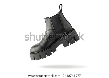 Trendy fashionable black leather short womens chelsea boot with rough sole flying isolated on white background. Casual style.
