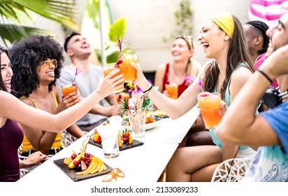 Trendy friends drinking cocktails at poolside party - Young people having fun on luxury resort - Fancy life style concept with guys and girls toasting drinks and fruit together - Bright vivid filter - Shutterstock ID 2133089233