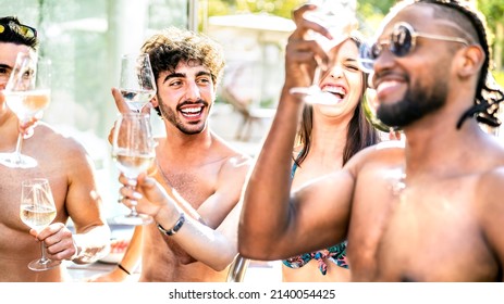 Trendy friends drinking white wine champagne at swimming pool party - Vacation life style concept with young guys and girls having fun together on summer day at luxury resort - Warm bright filter - Powered by Shutterstock