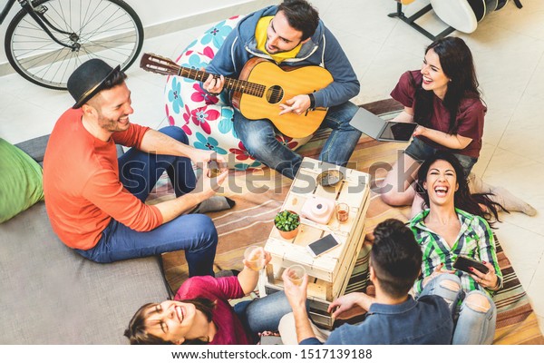 Trendy\
friends having fun in hostel at party night - Happy travel people\
enjoying time together playing music - Friendship, nightlife and\
youth concept - Main focus on right girls\
faces