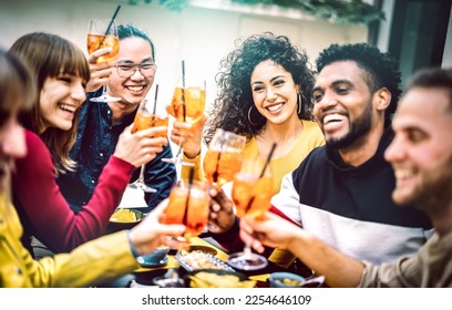 Trendy friends toasting spritz cocktail at bar restaurant - Life style concept with young people having fun together sharing drinks on happy hour at garden party - Vivid contrast filtered color tones