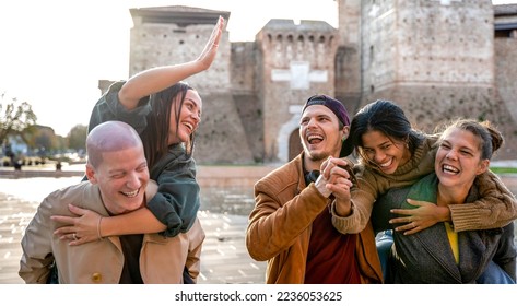 Trendy friends walking at city on piggy back move - Lifestyle concept with happy guys and girls having fun together outdoors -People meet after not seeing each other for long time-Focus on central men - Shutterstock ID 2236053625