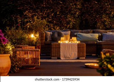 Trendy furniture, lights, lanterns and candles in the garden at night