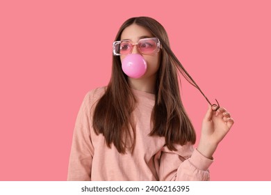 Chica de moda soplando chicle en fondo rosa
