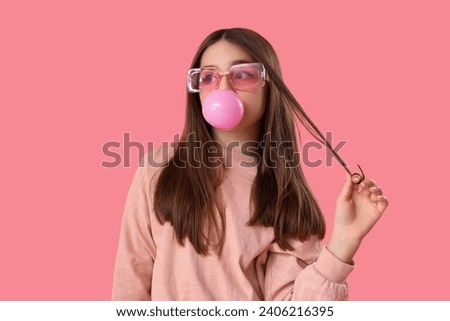 Trendy girl blowing bubble gum on pink background