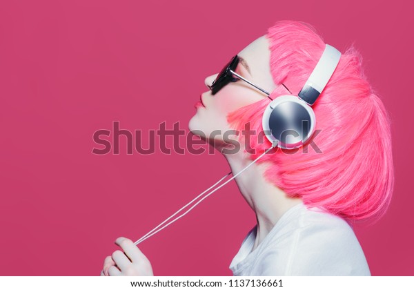サングラスをかけたピンクの髪のトレンディな女の子は ヘッドフォンで音楽を楽しみます ピンクの背景 若いスタイル 余暇 の写真素材 今すぐ編集