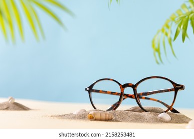 Trendy glasses in plastic frame on beach with palm leaves. Glasses sale poster. Optic store sale-out offer. Copy space. Optic store discount. Eyewear fasion promotion. Eyeglass Tortoiseshell frame
