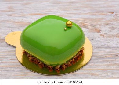 Trendy green mousse cake with mirror glaze decorated. wooden background. Close-up view