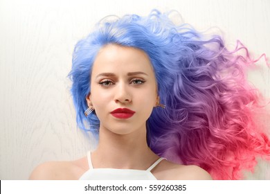 Trendy hairstyle concept  Young woman and colorful dyed hair white wooden background