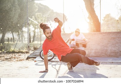 Trendy man making video feed of his breakdancer friend dancing in city park outdoor - Young people having fun sharing media online - Focus on dancer face - Youth lifestyle and friendship concept - Powered by Shutterstock