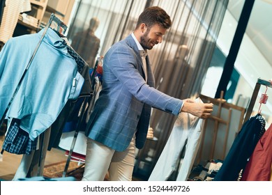 Un homme branché dans un magasin de vêtements pour hommes choisissant des pantalons. Il passe des pantalons et choisit ce qui lui convient le mieux. 