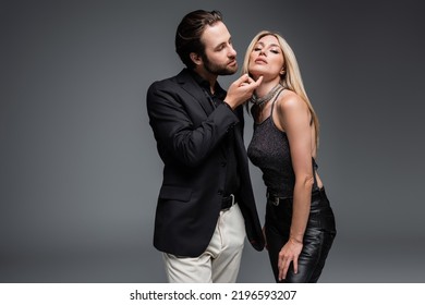 Trendy Man Touching Chin Of Blonde Girlfriend Isolated On Grey