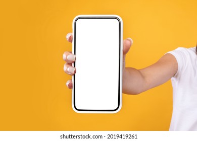 Trendy Mobile Phone. Closeup Of Female Holding Smartphone With White Empty Screen In Hand, Showing Device Close To Camera. Gadget With Blank Space, Mock Up, Selective Focus, Blurred Background