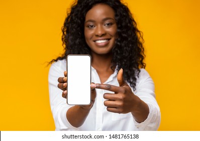 Trendy Mobile Phone. Smiling African American Woman Holding Latest Slim Smartphone With Blank Screen And Pointing At It.