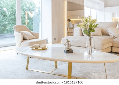trendy modern interior design of a large studio in white and beige colors with large floor-to-ceiling windows. area of ​​white kitchen with an island and a recreation area - Shutterstock ID 1815127100