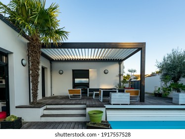 Trendy outdoor patio pergola shade structure, awning and patio roof, garden lounge, chairs, metal grill surrounded by landscaping - Shutterstock ID 1917557528
