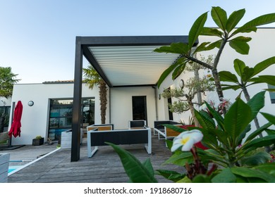 Trendy outdoor patio pergola shade structure, awning and patio roof, garden lounge, chairs, metal grill surrounded by landscaping - Shutterstock ID 1918680716