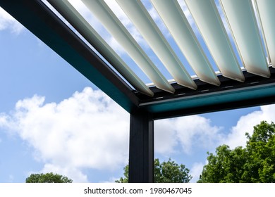 Trendy outdoor patio pergola. sky and clouds pass through the metallic structure. green trees in the background