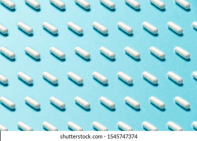 Trendy pattern made with Pharmaceutical medicine pills, tablets and capsules on bright light blue background. Medicine creative concepts. Minimal style with colorful paper backdrop. Trendy colors