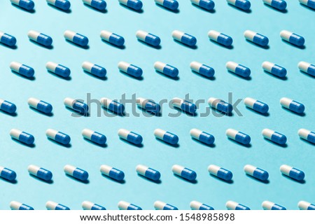 Trendy pattern made with Pharmaceutical medicine pills, tablets and capsules on bright light blue background. Medicine creative concepts. Minimal style with colorful paper backdrop. Trendy colors