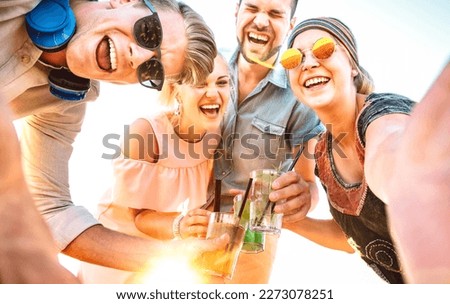 Trendy people group taking selfie at spring break festival toasting fancy cocktails at sunset - Summer joy and life style concept with young friends on happy hour time - Bright sunshine filter
