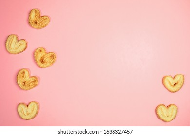 Trendy pink pastel background with heart shape cookies and copy space for text in middle. Holiday pastries for Valentine's day or Mother's day or Women's day. Top view, flat lay.
