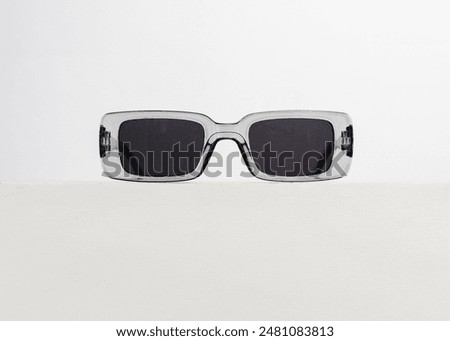 Trendy rectangular sunglasses with transparent grey frame and black lens color, isolated on white background
