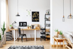 Trendy Room With Workspace For A Freelancer With White Wall, Desk, Black Vintage Chair, Industrial Lamps, Poster And Wooden Sofa In Bright Open Living Room