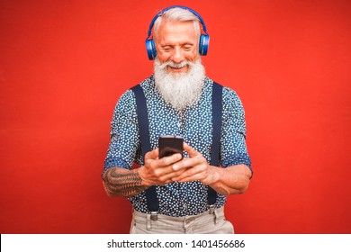 Trendy Senior Man Using Smartphone App With Red Backgorund - Mature Fashion Male Having Fun With New Trends Technology - Tech And Joyful Elderly Lifestyle Concept - Focus On His Face