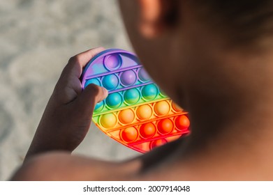 Trendy Silicon Fidgeting Game Sensory Toy Pop It In Kid's Hand In The Beach.Antistress Toy.Mental Concept