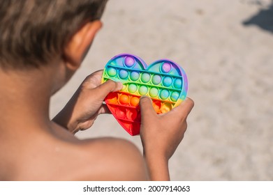 Trendy Silicon Fidgeting Game Sensory Toy Pop It In Kid's Hand In The Beach.Antistress Toy.Mental Concept