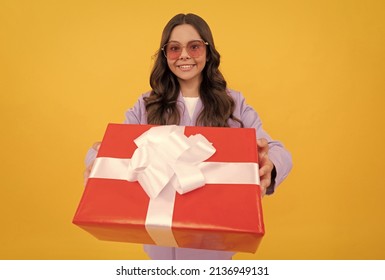 trendy smiling child in sunglasses and suit hold present box on yellow background, gift