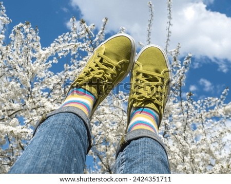 Trendy sneakers and colorful socks on the background of flowering trees. Closeup, outdoors. Men's and women's fashion style. Beauty and elegance concept