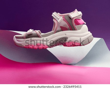 Trendy sport female grey-white-pink sandal with chunky sole on the multicolor paper background. Side view. Creative levitating concept. Copy space for text