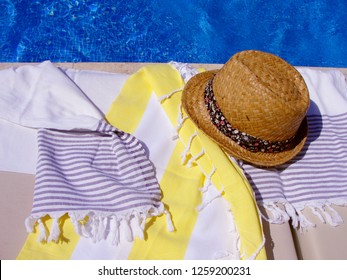 Trendy Straw Summer Hat And Cotton Towels On A Sunbed Near The Swimming Pool. Solar Glare On The Clear Water In The Pool. Bright Sunny Summer Vacation Day, Filtered Image, Solar Glare Filter