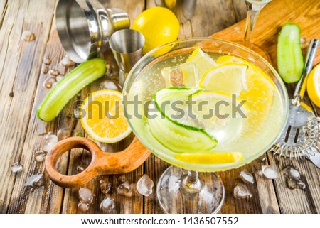 Trendy summer alcohol beverage, Low-Calorie and Low-Carb Tom Collins cocktail, with lemon and cucumber slices, old wooden background copy space
