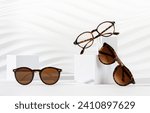 Trendy sunglasses of different design and eyeglasses on podiums on white background. Minimalism. Copy space. Sunglasses and spectacles sale concept. Optic shop promotion banner. Eyewear fashion