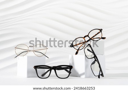 Trendy sunglasses of different design and eyeglasses on podiums on white background. Minimalism. Copy space. Sunglasses and spectacles sale concept. Optic shop promotion banner. Modern Eyewear fashion