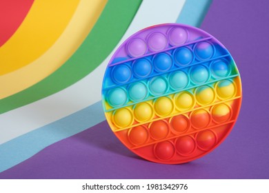 trendy toy antistress pop it on a rainbow background, fidget toy, popping bubbles and calm down, development of the motor skills of hands and fingers copy space
