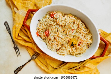 trendy vegan healthy food. pasta from feta cheese with small tomatoes in olive oil with herbs and spices in ceramic baking dish with yellow cotton napkin. step-by-step recipe, step 3. selective focus