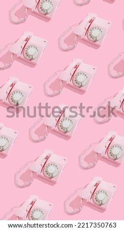 Trendy vertical pattern with old pink dial phones on bright sunny background. Retro communication concept. Vintage office.