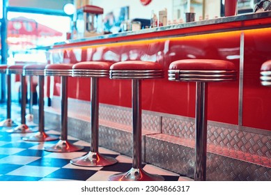 Trendy, vintage and retro interior in a diner, restaurant or cafeteria with funky decor. Booth, old school and chairs by a counter or bar in a groovy, vibrant and stylish old fashioned empty cafe.