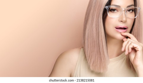 Trendy Woman In Clear Glasses Looking At Camera Posing In Studio. Fashion Eyewear And Clear Vision Concept. Beauty Portrait Over Beige Background With Copy Space