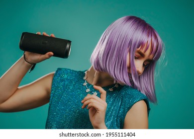 Trendy Woman With Dyed Purple Very Peri Hair Listening To Music By Wireless Portable Speaker - Modern Sound System. Young Lady Dancing, Enjoying On Turquoise Studio Background