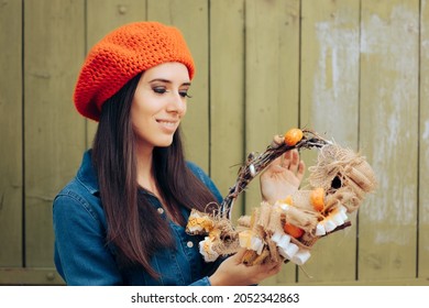 Trendy Woman Wearing a Beret Holding Autumn Wreath. Beautiful girl making a crafty artisanal handmade decoration for October holidays
				