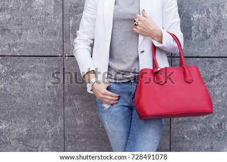 Trendy woman in white jacket with red bag in hand street look. Casual classic outfit