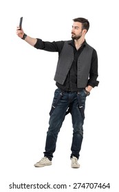 Trendy Young Man Taking Selfie Photo With His Mobile Phone. Full Body Length Portrait Isolated Over White Background.